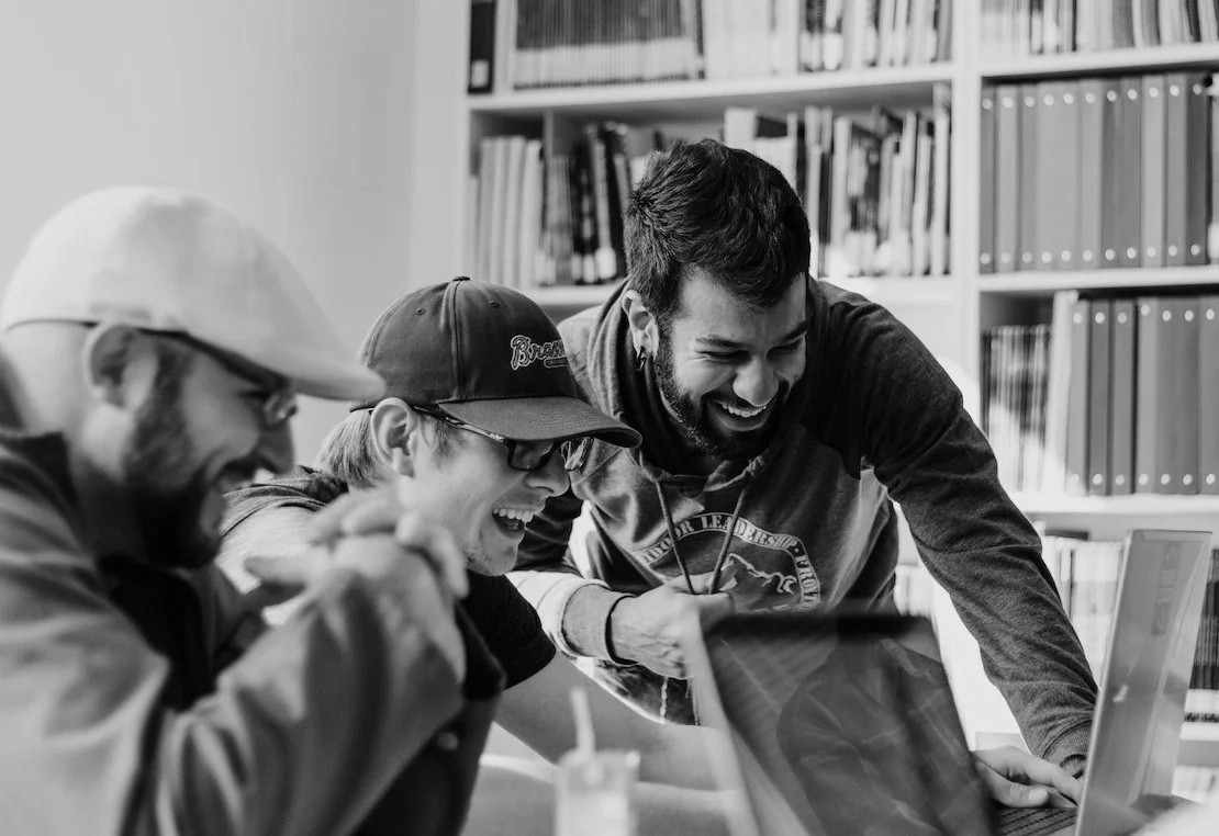 Clients laughing together while reviewing work on a laptop